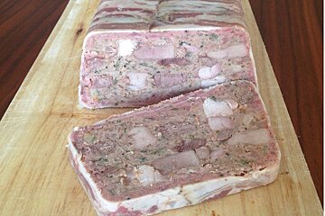 A loaf of meat is sitting on a wooden cutting board