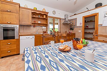 A kitchen with a clock on the wall and a table with a striped table cloth