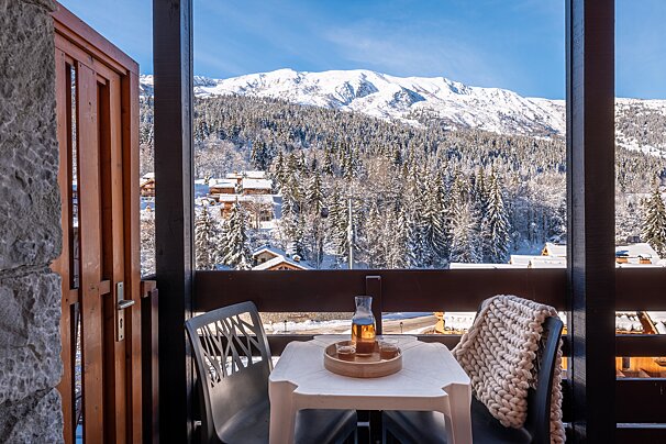 A balcony with a view of snowy mountains and trees
