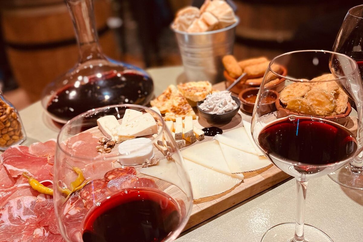 Two glasses of red wine sit next to a plate of food