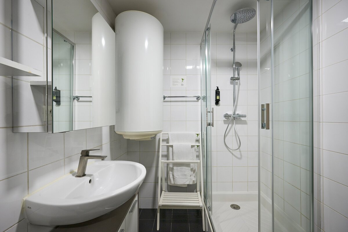 A bathroom with a sink a shower and a heater