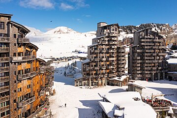 Snow covered buildings in a ski resort with mountains in the background