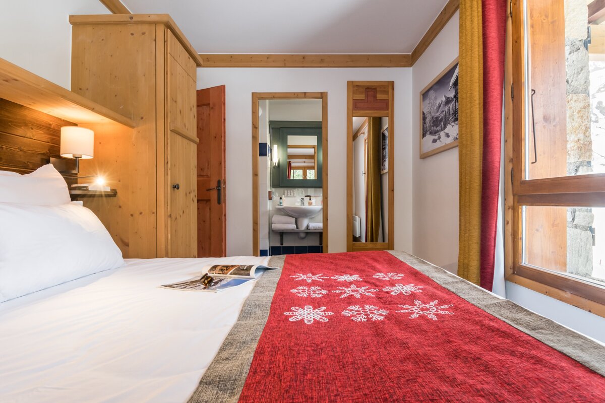 A bed with a red blanket with snowflakes on it