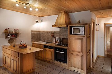 A kitchen with wooden cabinets and a microwave