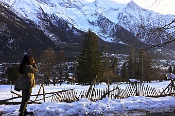 A woman taking a picture of a snowy mountain range