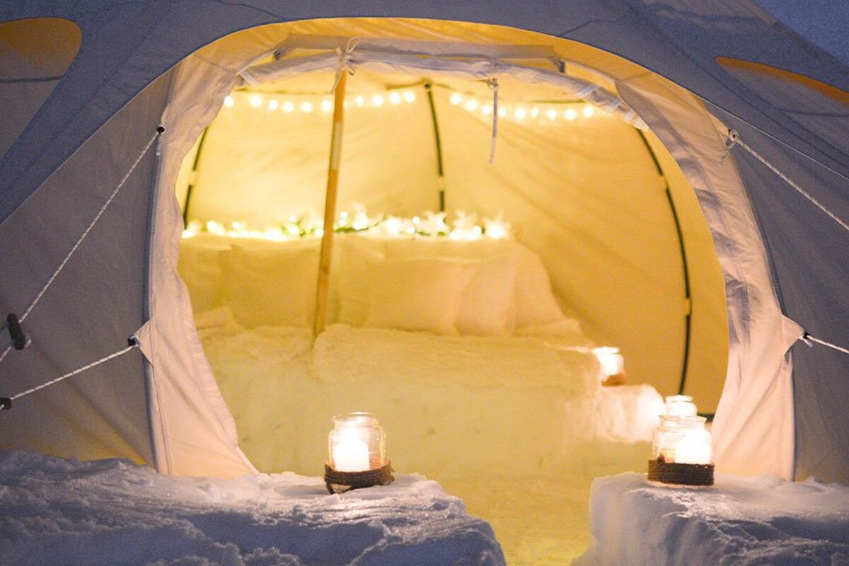 A tent is lit up with candles and snow