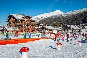 A group of children are playing in the snow in front of a hotel