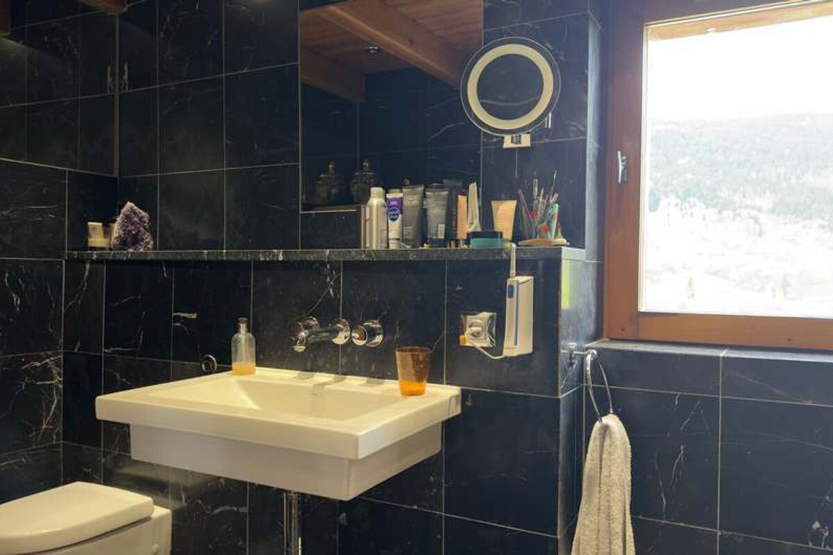 A bathroom with black tiles and a sink and toilet