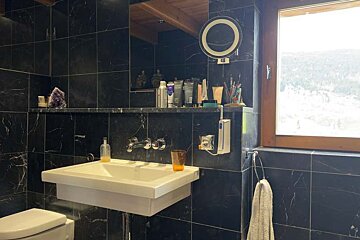 A bathroom with black tiles and a sink and toilet
