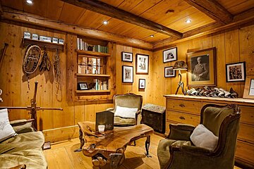 A wooden room with a couch and two chairs