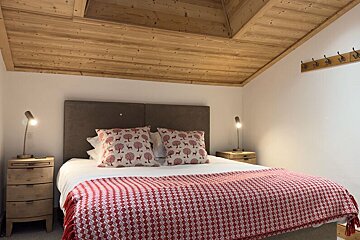A bedroom with a wooden ceiling and a bed