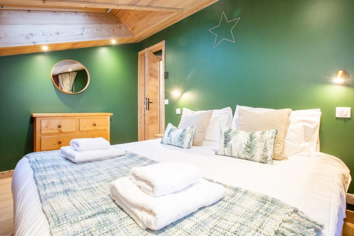 A bedroom with green walls and a bed with white sheets and pillows