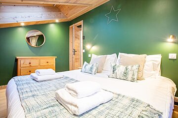 A bedroom with green walls and a bed with white sheets and pillows