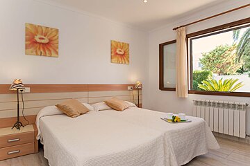 A bedroom with a large bed and two paintings on the wall