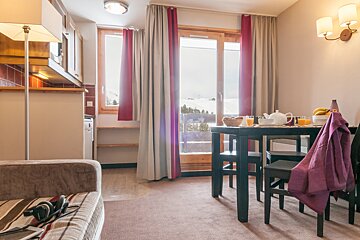 A living room with a table and chairs and a window