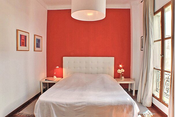 A bedroom with a red wall and a white bed