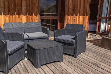 A wooden deck with wicker chairs and a table
