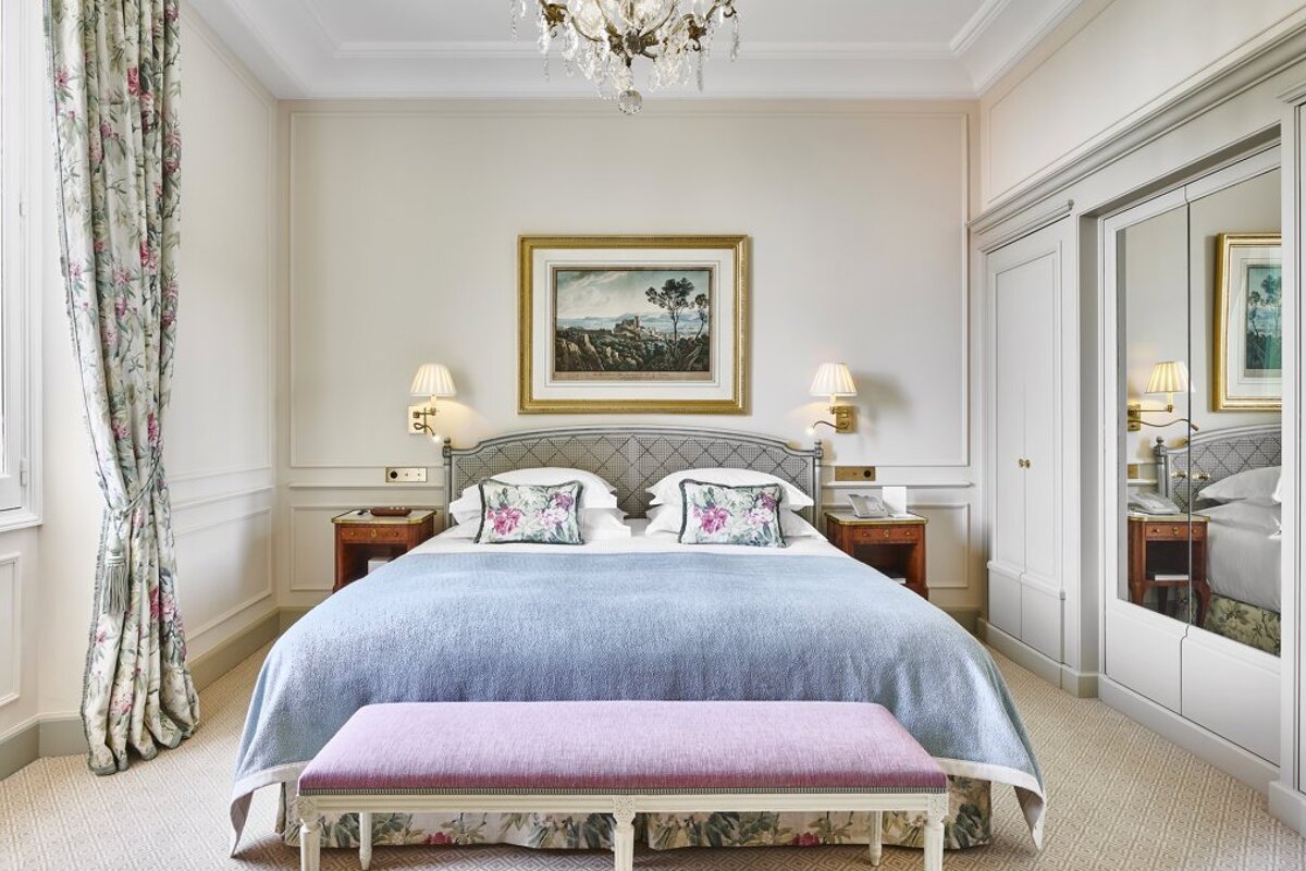 A bedroom with a painting on the wall above the bed