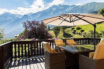 A large umbrella sits on a deck overlooking mountains