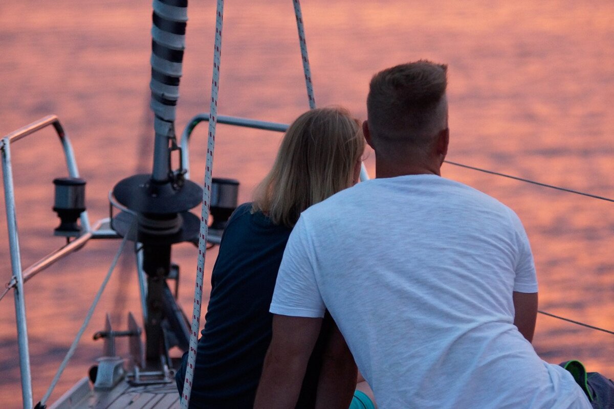 A man and a woman are sitting on a boat looking at the water