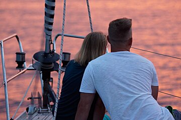 A man and a woman are sitting on a boat looking at the water