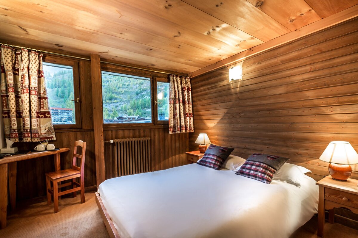 A bedroom with a bed a desk and two lamps