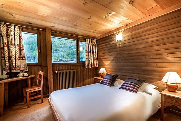 A bedroom with a bed a desk and two lamps
