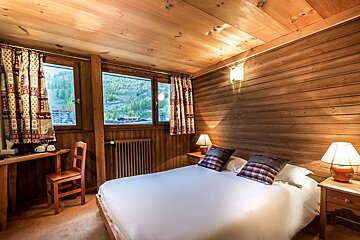 A bedroom with a bed a desk and two lamps