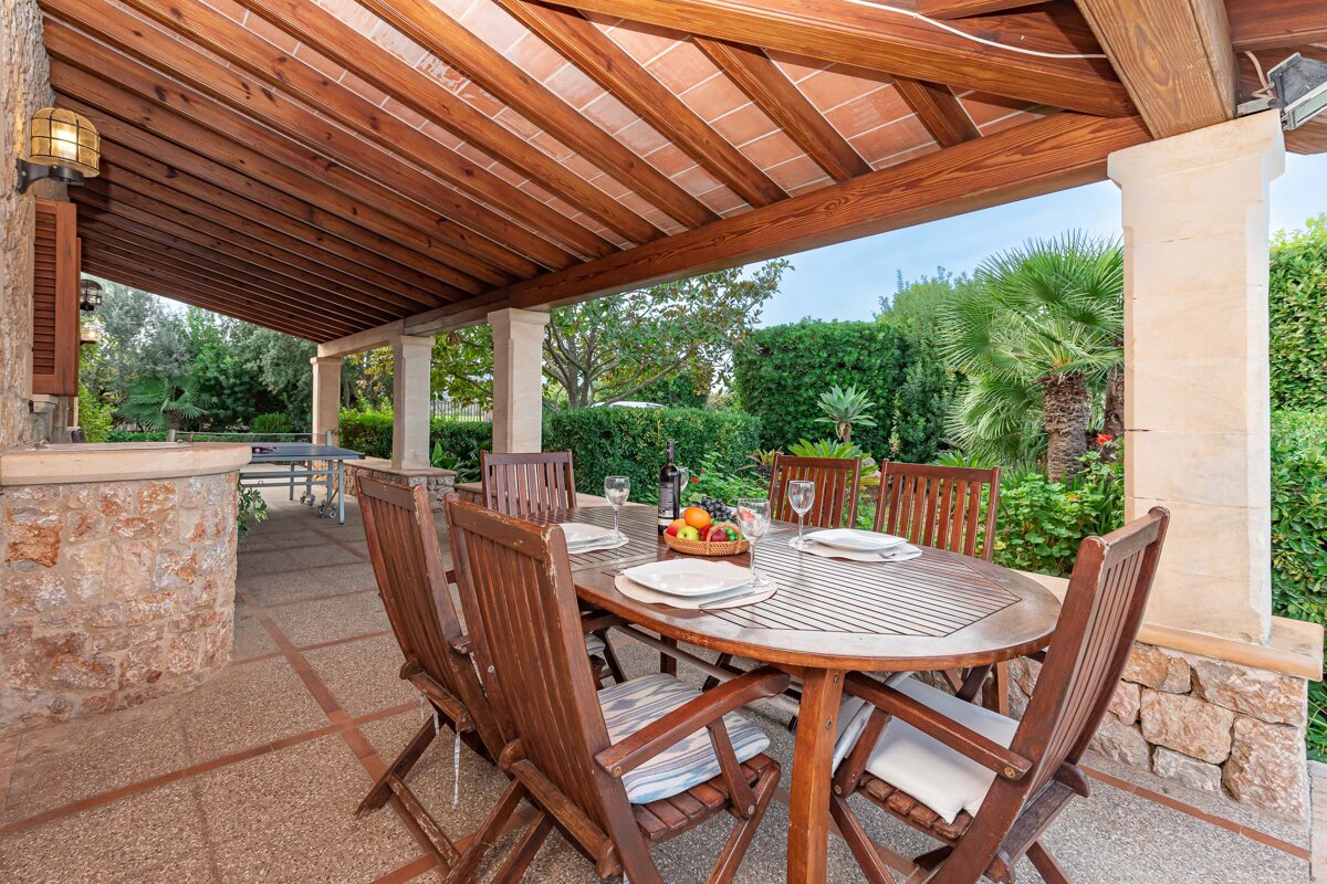 A patio with a table and chairs under a wooden roof