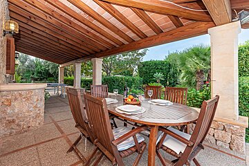 A patio with a table and chairs under a wooden roof