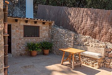 A wooden table sits in front of a stone wall