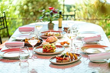 A table with plates of food and wine glasses on it