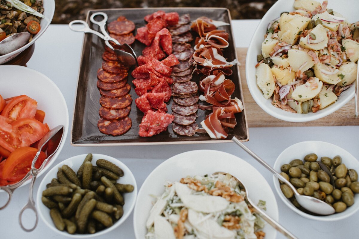 A buffet table with a plate of meat and a bowl of salad