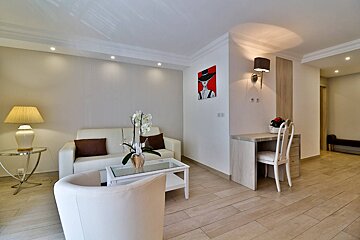 A living room with a couch and chairs and a painting on the wall