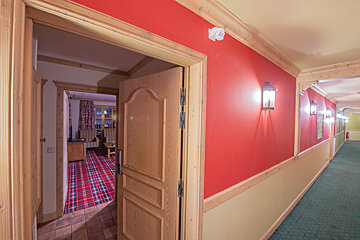 A hallway with red walls and a wooden door