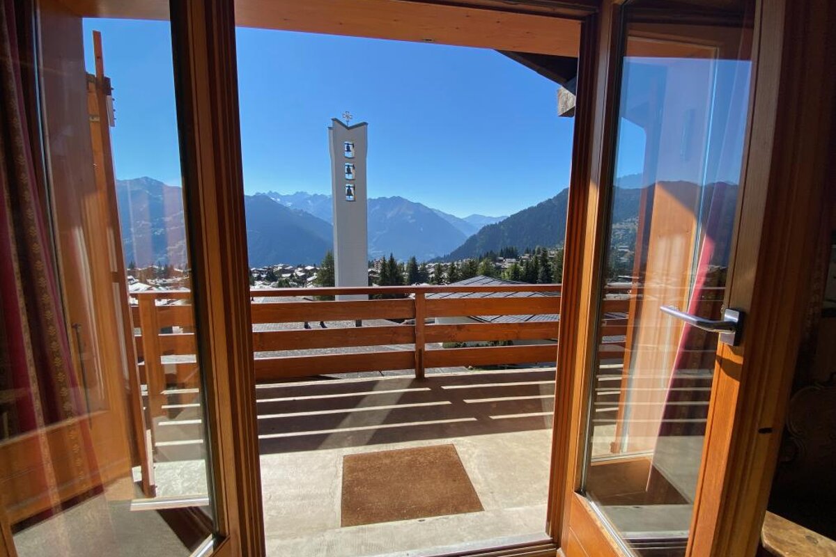 A balcony with a view of the mountains and a church tower