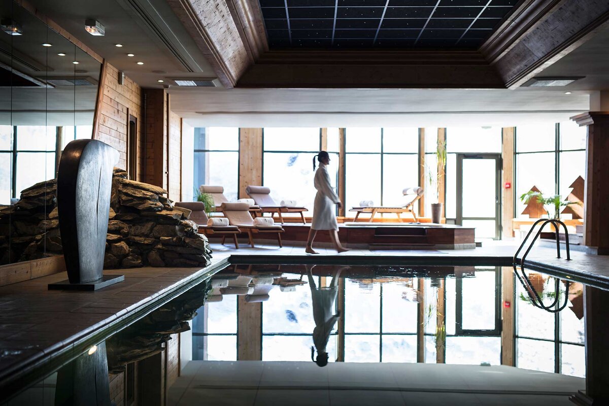 A woman in a bathrobe walks by a swimming pool