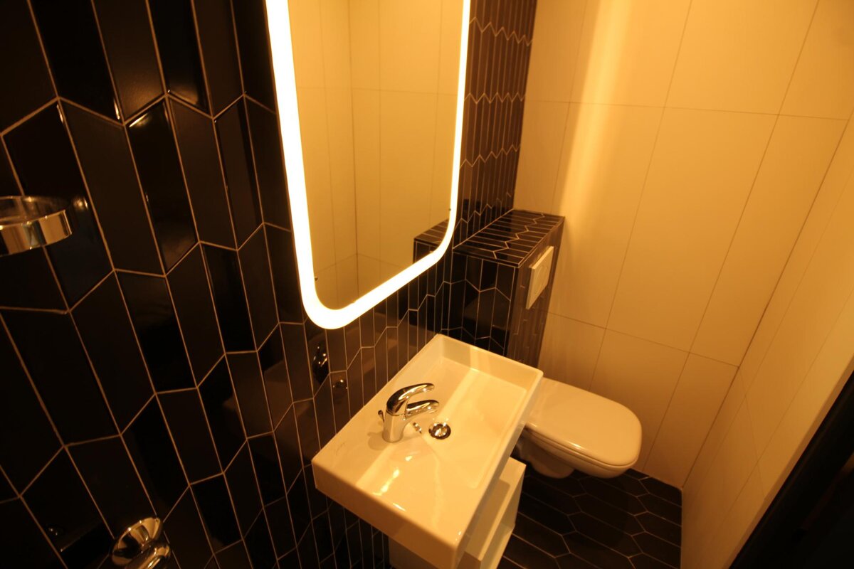 A bathroom with black tiles and a sink and toilet