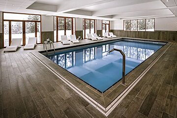 A large indoor swimming pool surrounded by chairs and windows