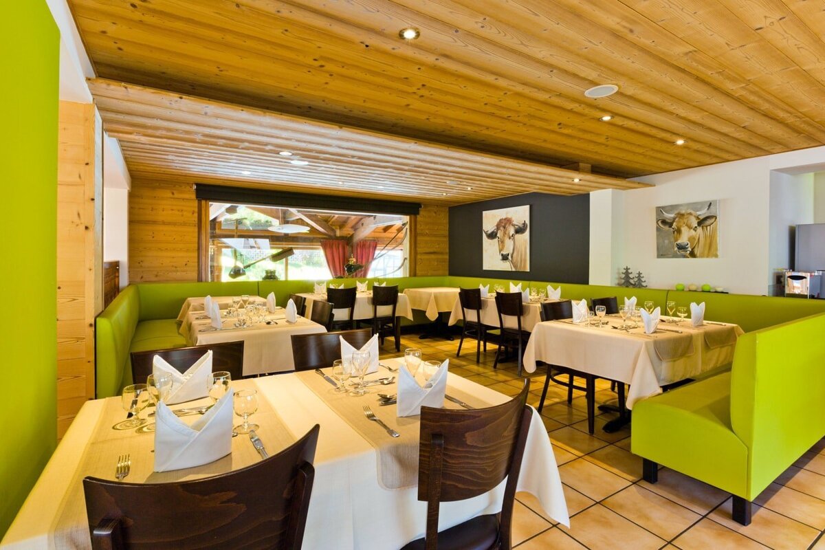 A restaurant with tables and chairs and a painting of a cow on the wall