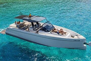 People sunbathing on a modern white motorboat floating in crystal-clear turquoise water.