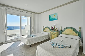 A bedroom with two beds and a painting on the wall