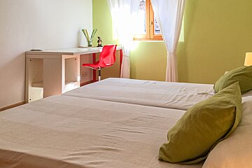 A bedroom with two beds and a desk in the corner
