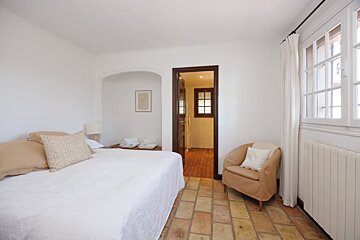 A bedroom with a white bed and a chair