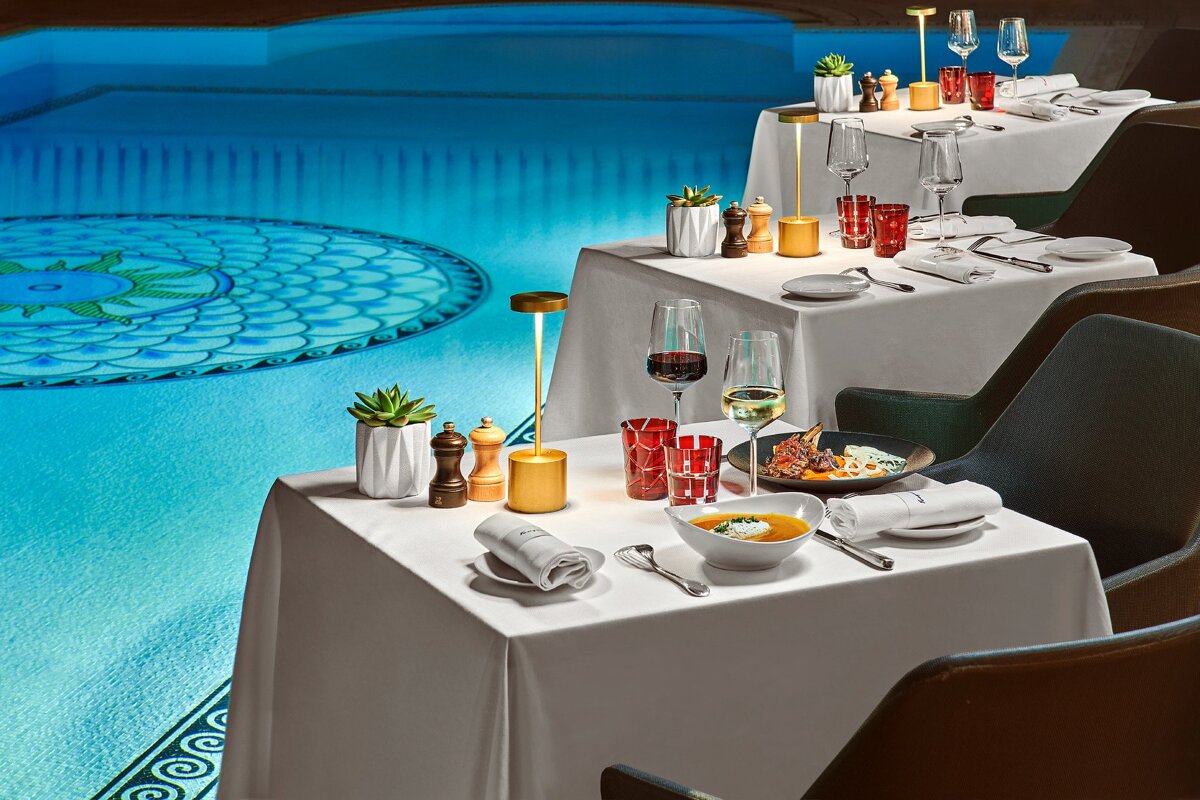 A table with a bowl of soup on it in front of a pool