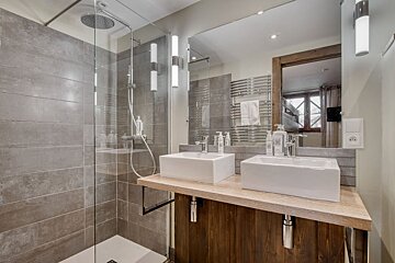 A bathroom with two sinks and a walk in shower