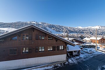 A car is parked in front of a snowy house