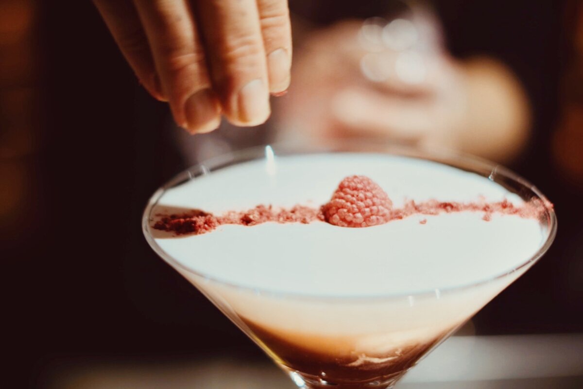 A martini with a raspberry on top of it