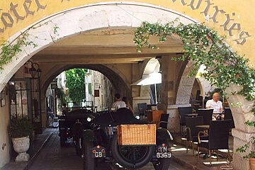 Two old cars are parked under an archway with the license plate gb 8369