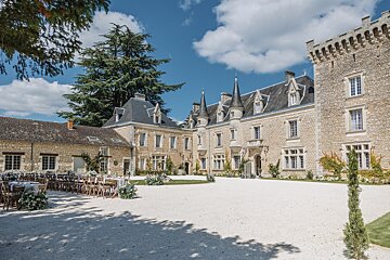 Tables and chairs are set up in front of a large stone building